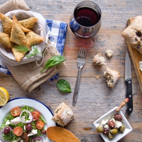Traditional Greek dishes with red wine, salad, olives, and pastries – GW The Greek Wine Routes, authentic Greek food and wine culture.